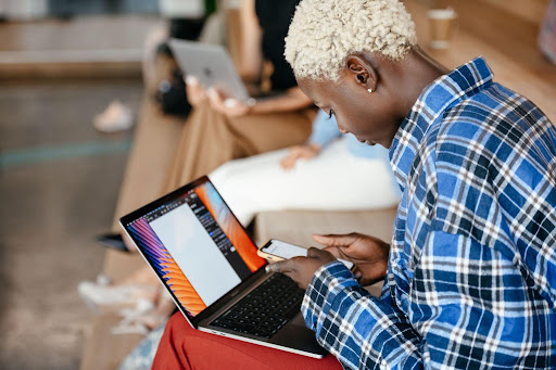 Person in a plaid shirt using a laptop and smartphone