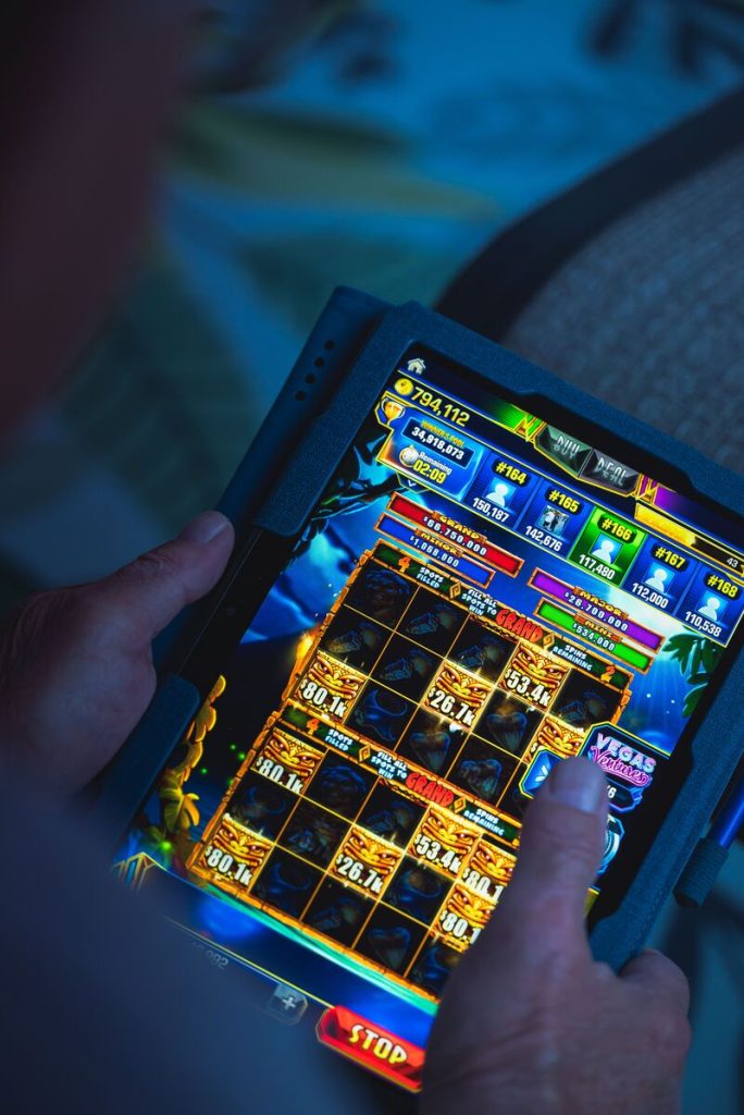 Hand tapping a colorful slot-style casino game on a tablet touchscreen